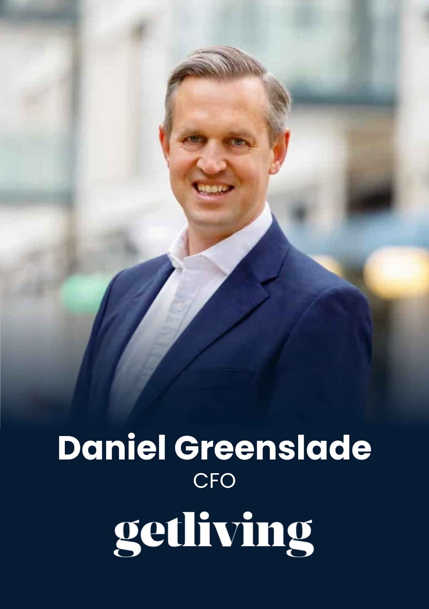 Head-and-shoulders portrait of Daniel Greenslade, CEO, in a navy blazer and white shirt, smiling with a blurred urban background.