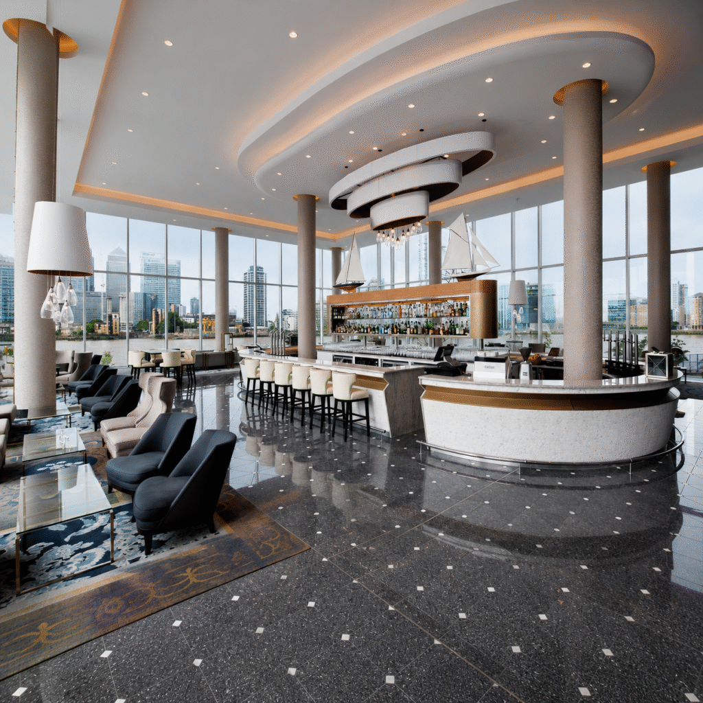 Luxurious hotel lounge with a curved ceiling, tall columns, and a long marble bar overlooking a city skyline through expansive windows.