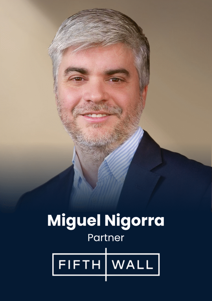 Head-and-shoulders portrait of Miguel Nigora, business partner, in a navy blazer and striped shirt against a neutral gradient background (professional headshot).