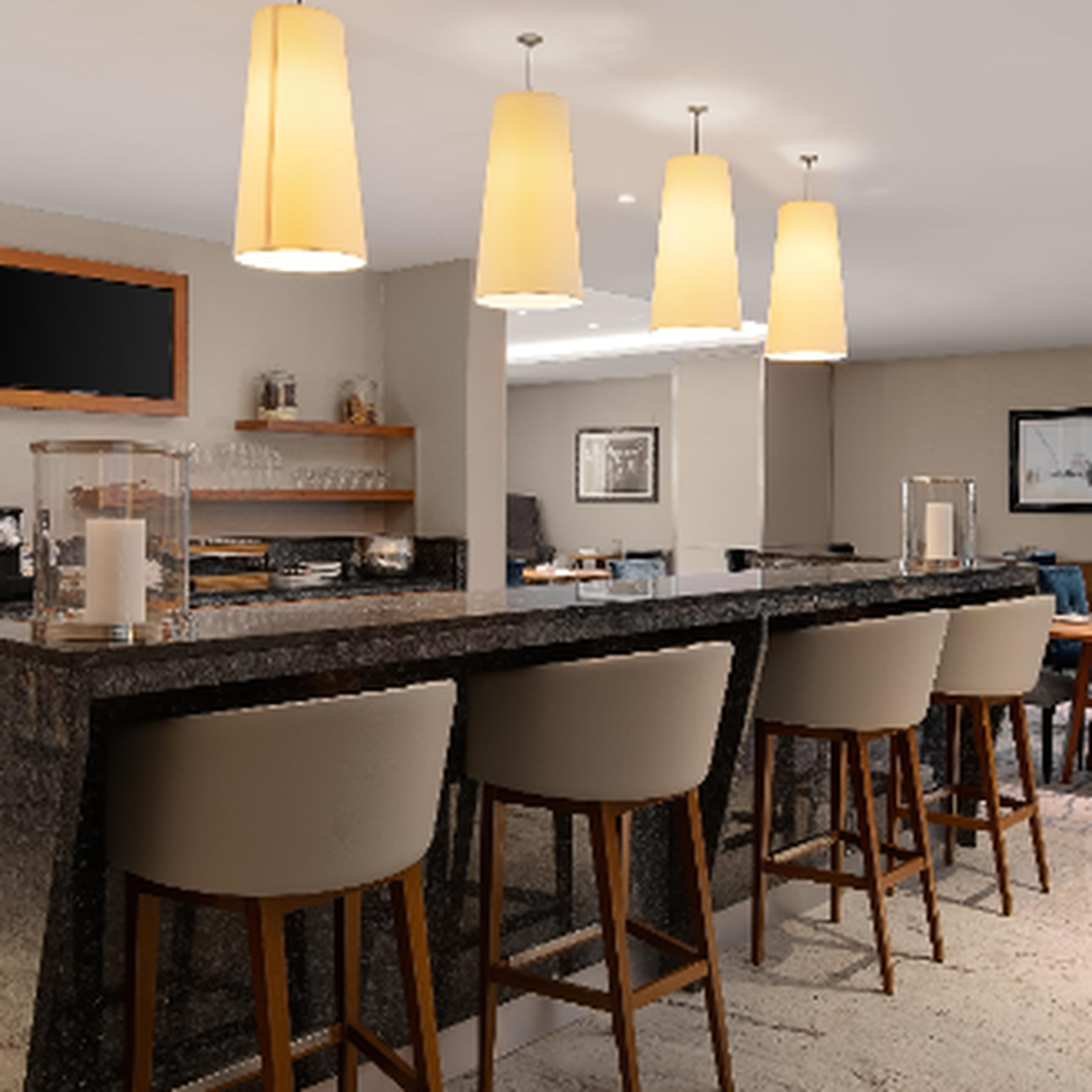 Hotel-style bar with a dark granite counter and beige stools under warm pendant lights.