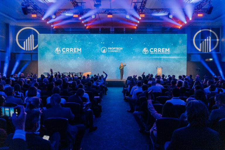Speaker on stage addressing a large audience at a tech conference with CRREM and PropTech Connect logos on the screen behind him/her.