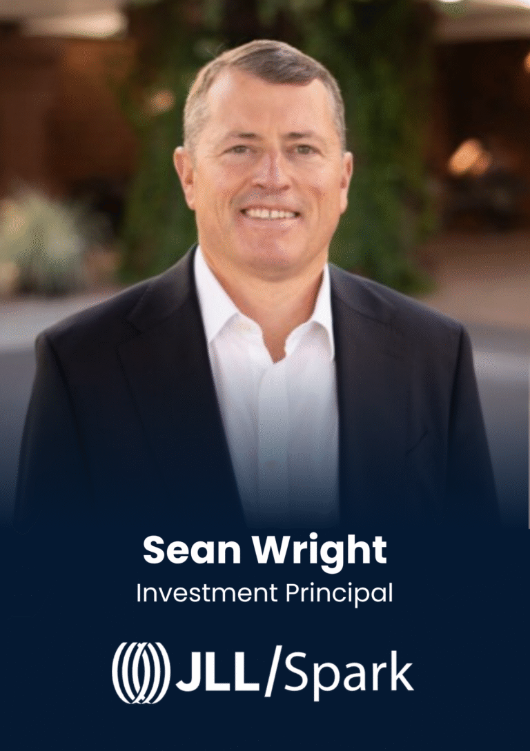 Portrait of Sean Wright, Investment Principal, smiling in a dark suit and white shirt.