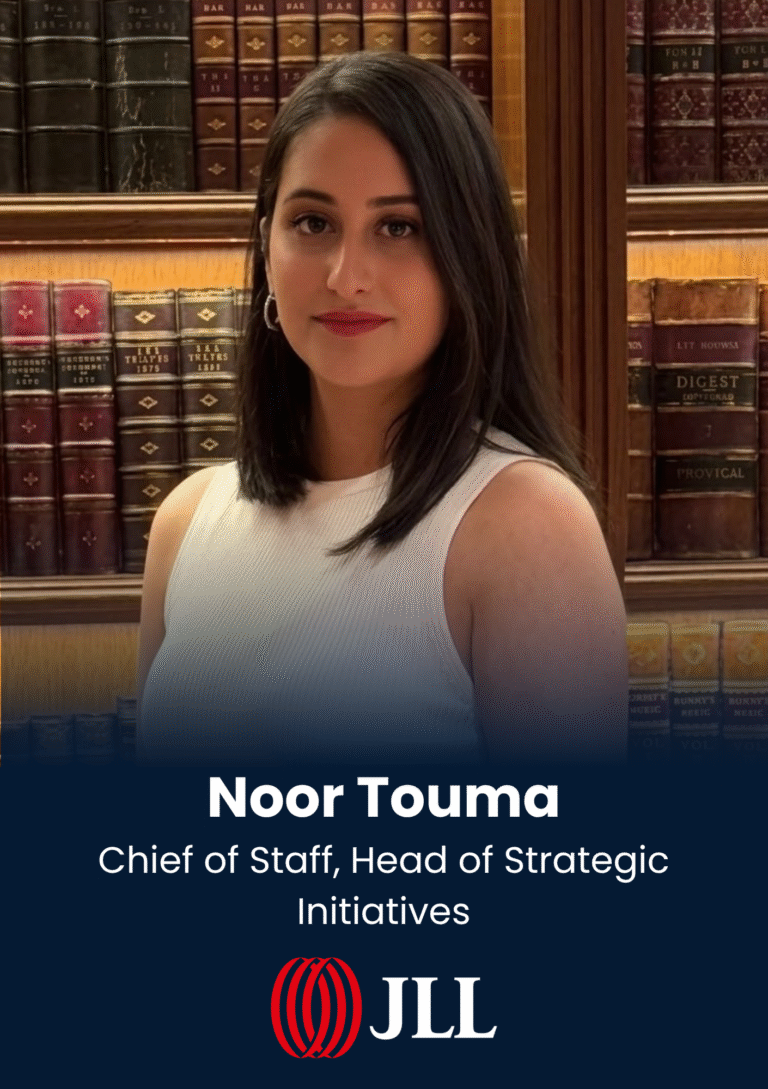Portrait of Noor Touma, Chief of Staff and Head of Strategic Initiatives, standing in a library with leather-bound books behind her.