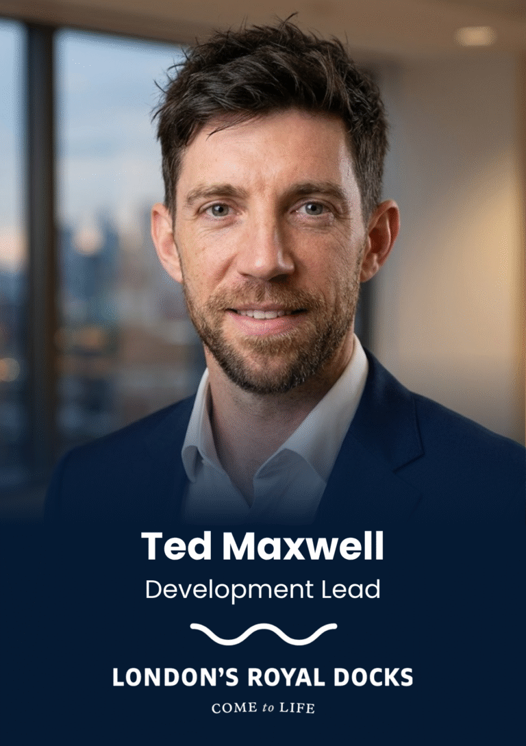 Portrait of Ted Maxwell, Development Lead, in a navy suit in an office setting with a cityscape background.