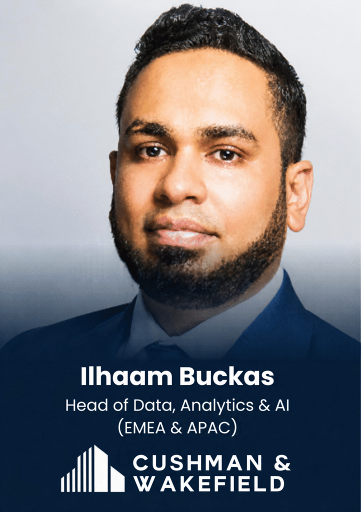 Portrait of a man in a blue suit against a gray background, used as a speaker/profile photo (name shown on slide: Ilham Buckcas).