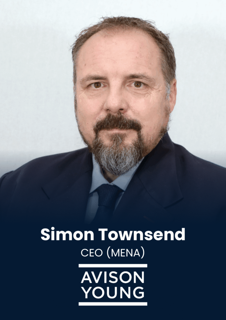 Professional headshot of a man with a beard in a dark suit against a light backdrop, looking at the camera.