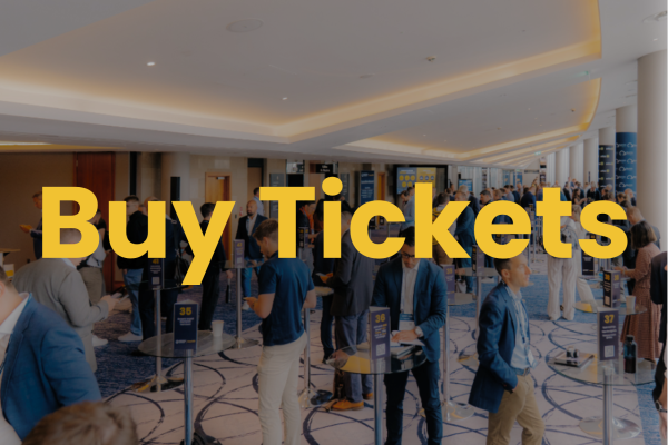 'Buy Tickets' displayed in bold yellow text over a blurred background of people and a structure, prompting ticket purchase.